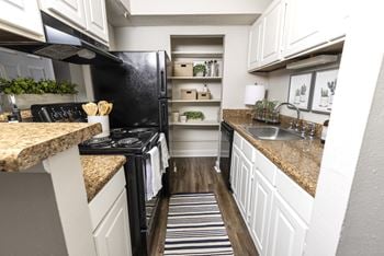 A kitchen with white cabinets and a black stove top oven
